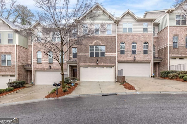 townhome / multi-family property featuring a garage, brick siding, and concrete driveway