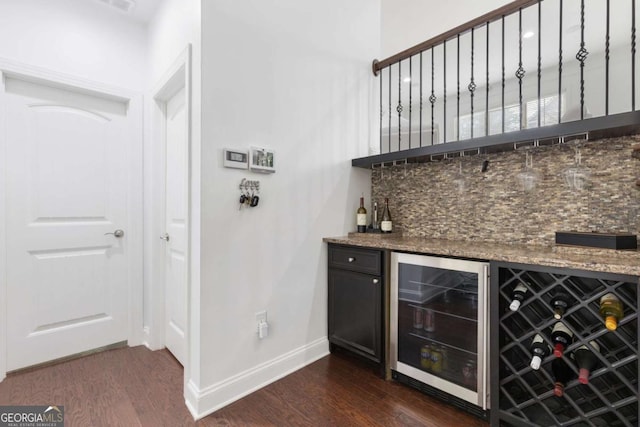 bar with a dry bar, beverage cooler, dark wood-style flooring, and baseboards