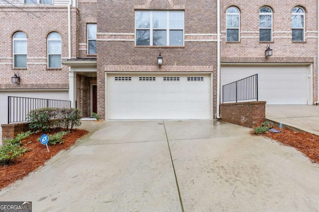 townhome / multi-family property featuring brick siding, driveway, and a garage