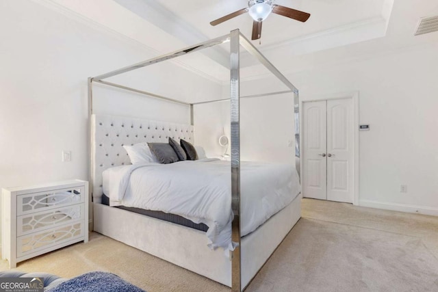 carpeted bedroom featuring visible vents, crown molding, baseboards, ceiling fan, and a tray ceiling