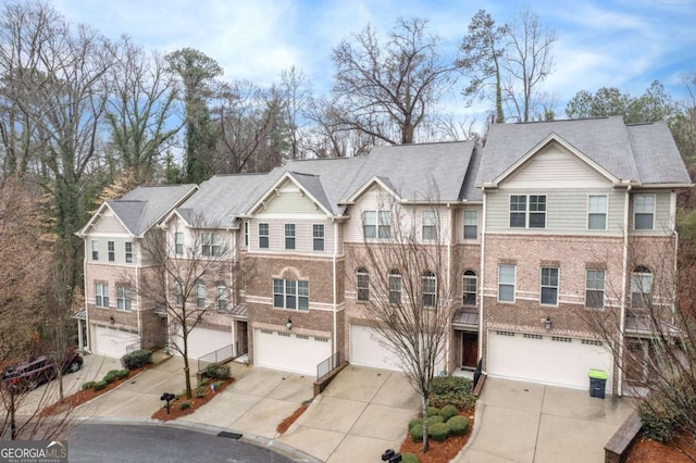 multi unit property featuring brick siding, concrete driveway, and a garage