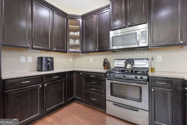 kitchen with light stone counters, decorative backsplash, appliances with stainless steel finishes, and dark wood-style flooring