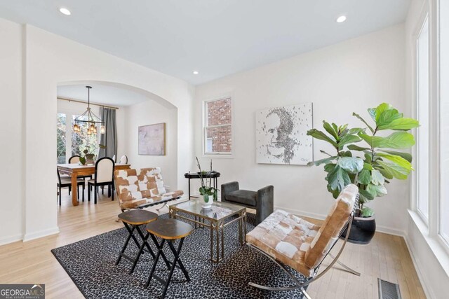 living room with visible vents, recessed lighting, arched walkways, light wood finished floors, and baseboards