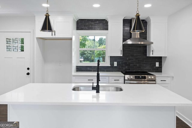 kitchen featuring stainless steel electric range oven, decorative backsplash, white cabinets, wall chimney exhaust hood, and a sink