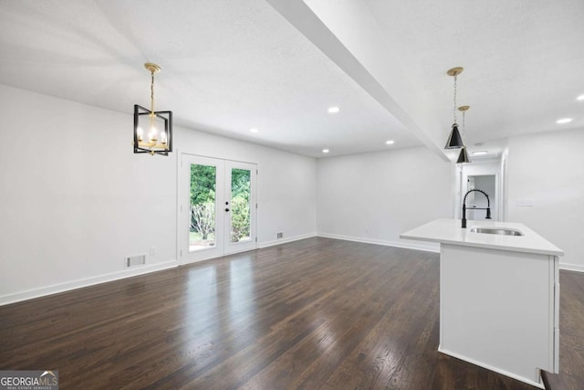 unfurnished living room with visible vents, dark wood-style flooring, baseboards, and a sink