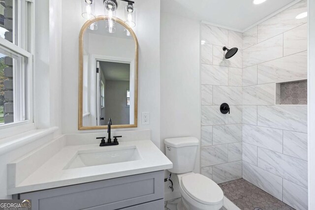 full bathroom with toilet, vanity, and a tile shower