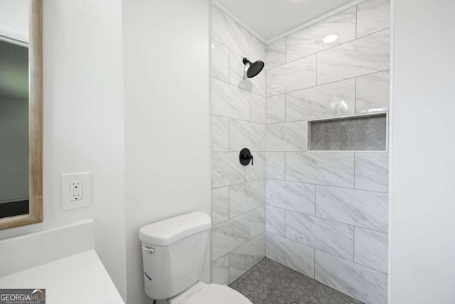 full bathroom with a tile shower and toilet