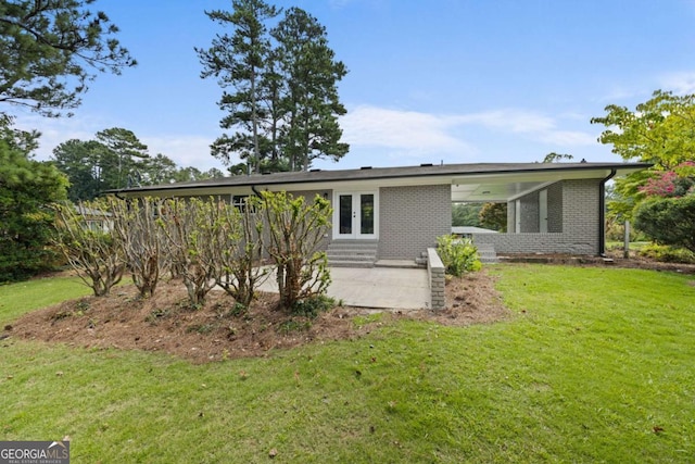 rear view of property featuring french doors, a lawn, brick siding, and a patio area