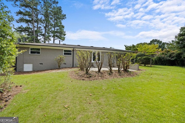 back of property with crawl space, a lawn, and brick siding