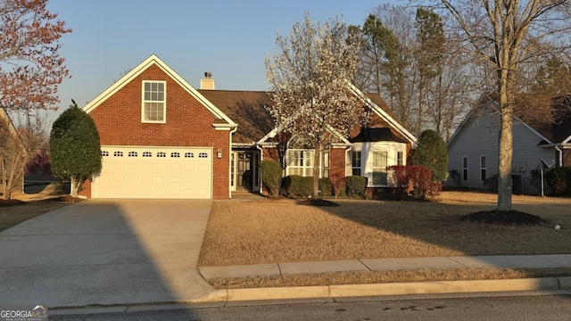 view of front of house with brick siding, an attached garage, concrete driveway, and a chimney