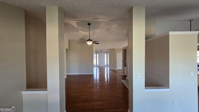 corridor featuring a textured ceiling, dark wood-type flooring, and baseboards