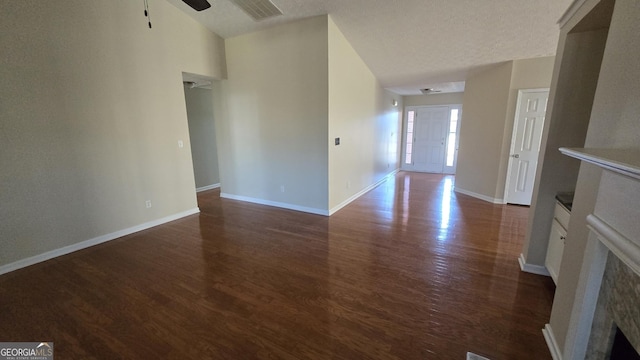 unfurnished living room featuring a ceiling fan, dark wood-style floors, visible vents, and baseboards