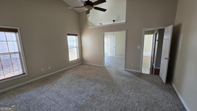 spare room with carpet flooring, a ceiling fan, baseboards, and high vaulted ceiling