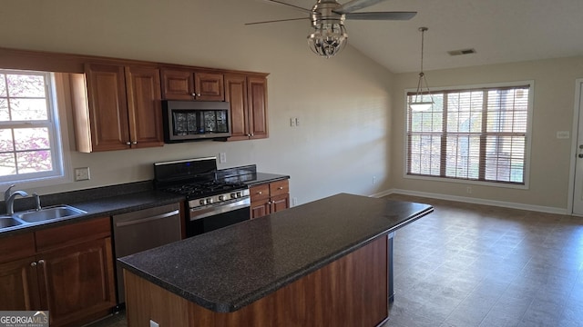 kitchen with a sink, dark countertops, a center island, appliances with stainless steel finishes, and lofted ceiling