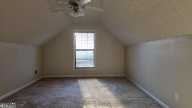 bonus room featuring a textured ceiling, carpet, baseboards, ceiling fan, and vaulted ceiling