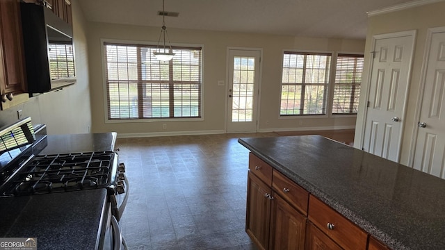 kitchen featuring baseboards, gas range, dark countertops, and plenty of natural light