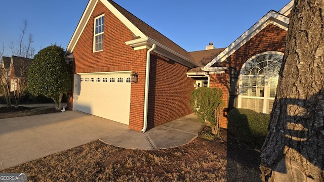 view of home's exterior with a garage, brick siding, and concrete driveway