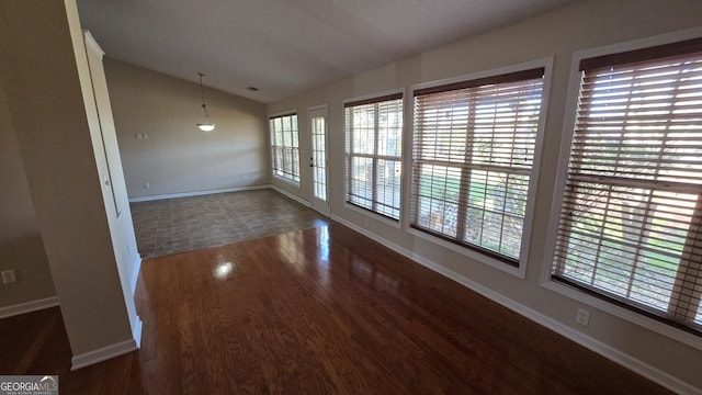 empty room with baseboards, lofted ceiling, visible vents, and wood finished floors