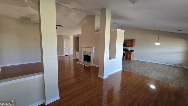 unfurnished living room with a high end fireplace, dark wood finished floors, baseboards, and ceiling fan