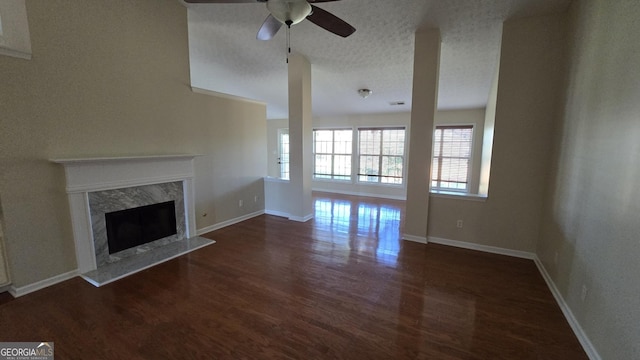 unfurnished living room featuring dark wood finished floors, a textured ceiling, a ceiling fan, and a premium fireplace