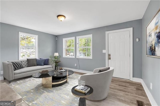 living room with plenty of natural light, wood finished floors, visible vents, and baseboards