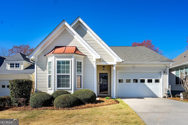 view of front of property with concrete driveway, a garage, roof with shingles, and a front lawn