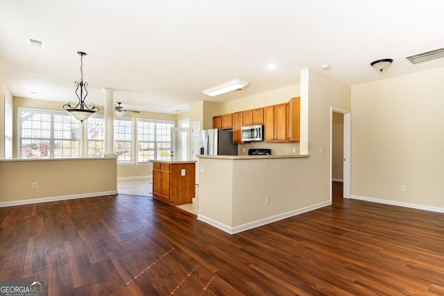 kitchen with dark wood-type flooring, brown cabinetry, visible vents, and stainless steel appliances