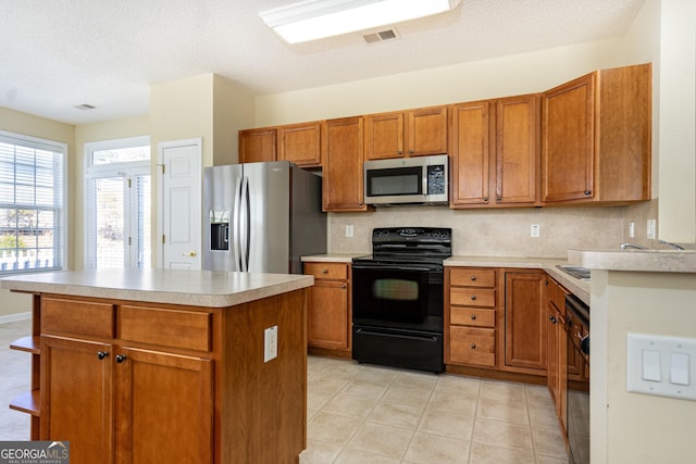 kitchen featuring visible vents, black appliances, backsplash, brown cabinetry, and light countertops