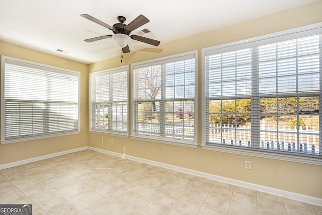 unfurnished sunroom with visible vents and ceiling fan