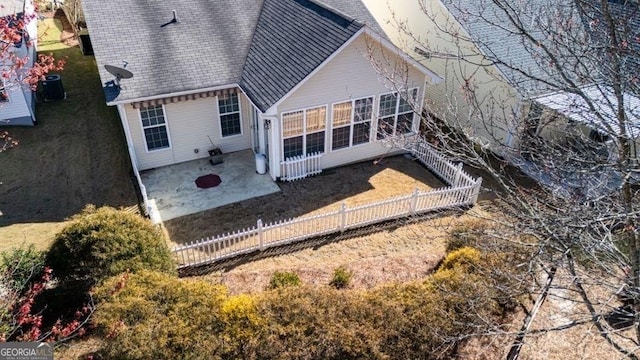 rear view of house featuring fence, a shingled roof, and a patio area