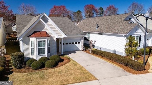 view of front facade with driveway, roof with shingles, and an attached garage