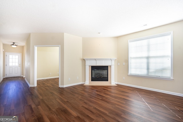 unfurnished living room featuring dark wood-type flooring, a fireplace, baseboards, and visible vents