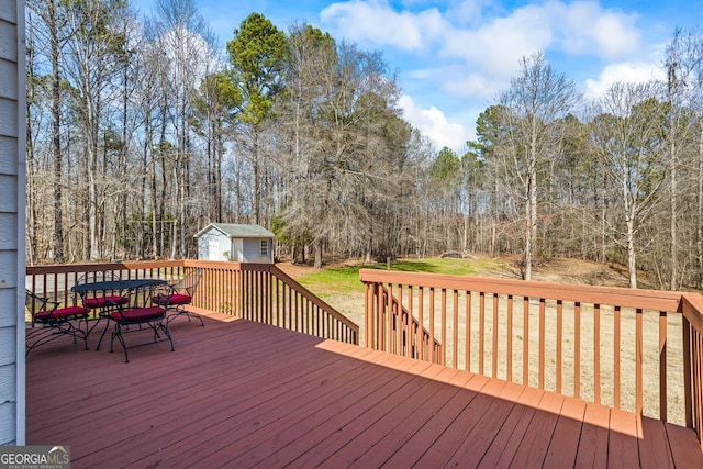 deck with a storage unit, an outbuilding, and outdoor dining space