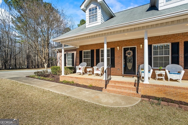 view of exterior entry featuring brick siding and a porch