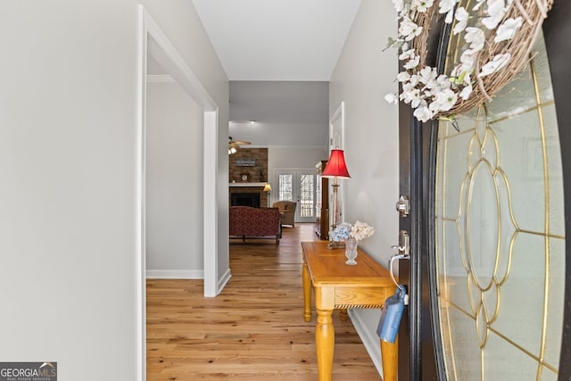 entryway featuring a fireplace, wood finished floors, and ceiling fan