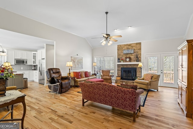 living room featuring ornamental molding, a stone fireplace, light wood finished floors, lofted ceiling, and ceiling fan