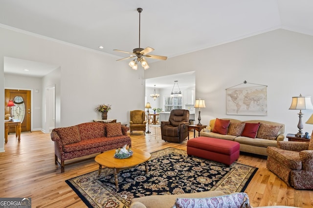 living room featuring light wood finished floors, ceiling fan with notable chandelier, lofted ceiling, and ornamental molding