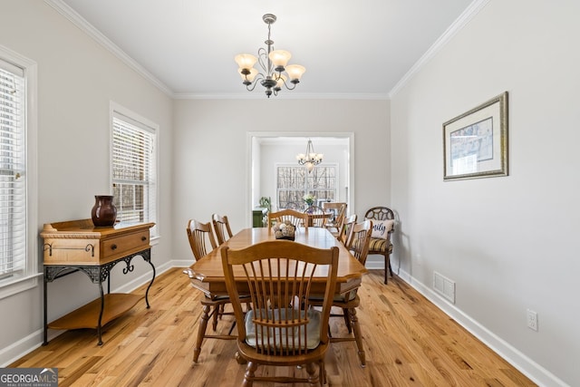 dining space with a chandelier, light wood-style flooring, crown molding, and baseboards