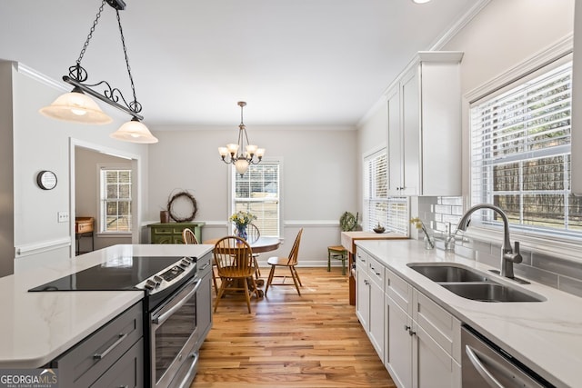 kitchen with ornamental molding, appliances with stainless steel finishes, light wood-style floors, white cabinets, and a sink