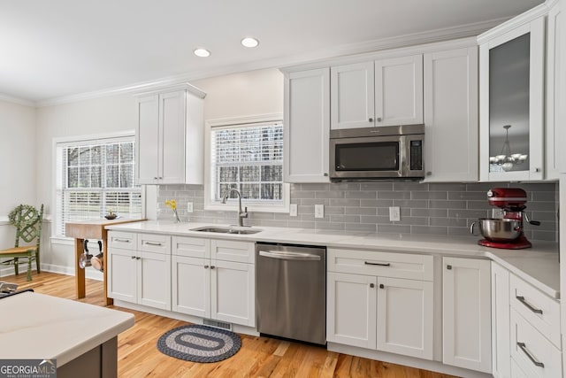 kitchen with ornamental molding, a sink, plenty of natural light, stainless steel appliances, and light countertops