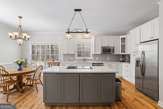 kitchen with a sink, tasteful backsplash, white cabinetry, appliances with stainless steel finishes, and light countertops