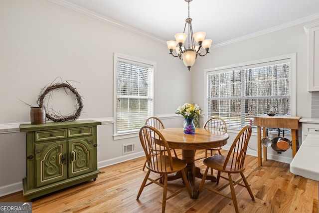 dining room featuring light wood-type flooring, visible vents, crown molding, baseboards, and a chandelier