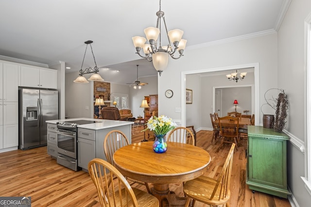 dining area with light wood-style flooring, ceiling fan with notable chandelier, and ornamental molding