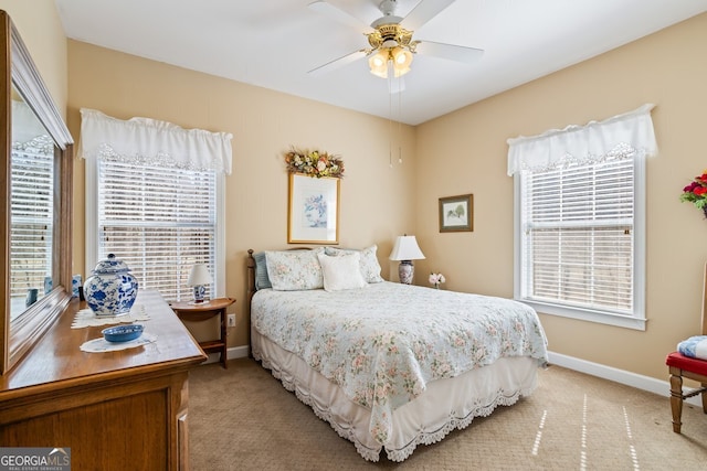 bedroom featuring light carpet, multiple windows, baseboards, and ceiling fan