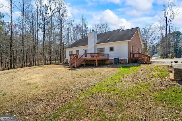 back of property with a chimney, stairs, a deck, central air condition unit, and a lawn