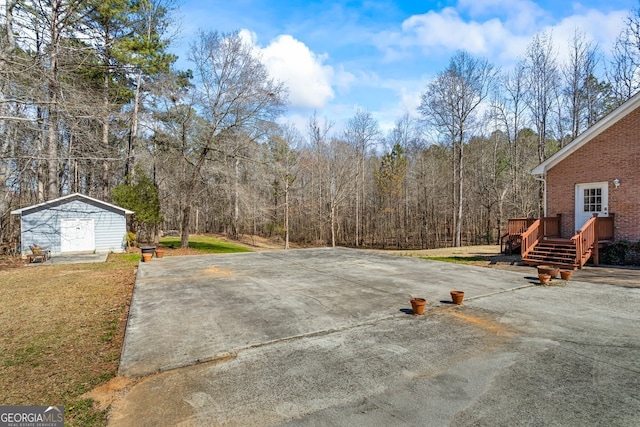 view of patio / terrace with an outbuilding, a wooded view, and a deck