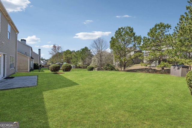 2311 Fall Creek Lndg, Loganville, GA 30052 - view of green lawn with a storage unit and a patio