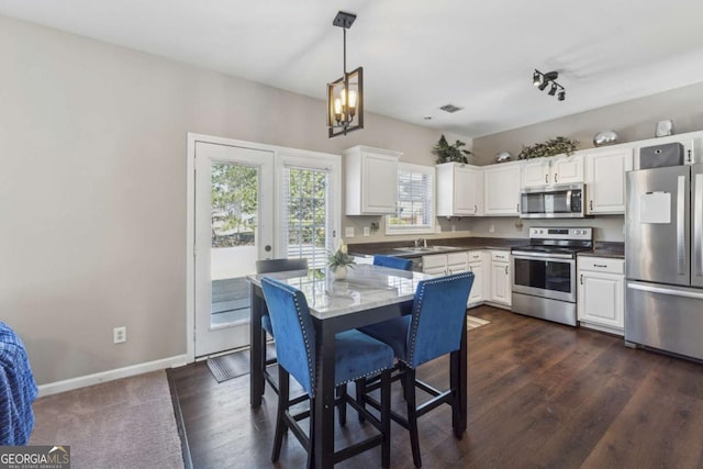 2311 Fall Creek Lndg, Loganville, GA 30052 - kitchen featuring stainless steel appliances, white cabinets, hanging light fixtures, dark wood-style flooring, and a chandelier