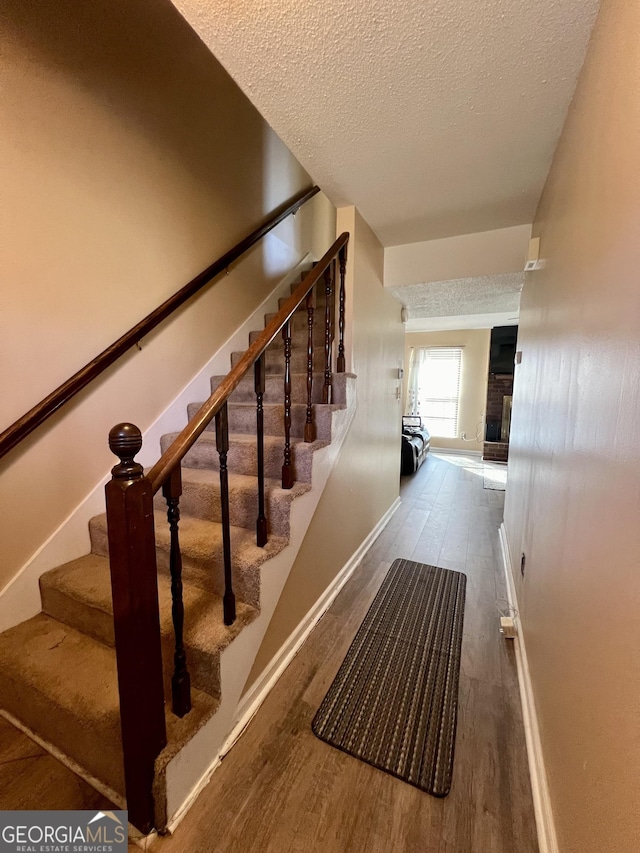 stairs with baseboards, a textured ceiling, and wood finished floors