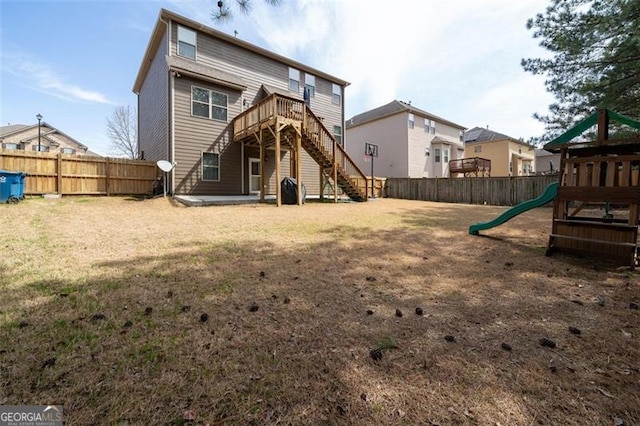 rear view of house with a yard, a fenced backyard, stairs, and a playground